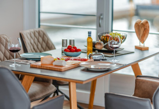 Et elegant dækket bord på Houseboat am Bärwalder See med vin, ost, frugt og udsigt til søen.