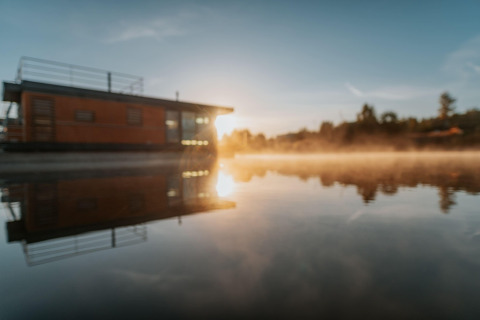 Sunrise at Houseboat am Bärwalder See with beautiful water reflection and morning mist on the lake.