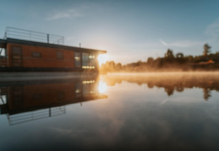 Sunrise at Houseboat am Bärwalder See with beautiful water reflection and morning mist on the lake.
