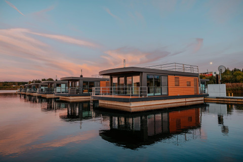 Modernos barcos-casa en Bärwalder See al atardecer, reflejados en aguas tranquilas y entorno apacible.