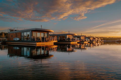 Houseboat am Bärwalder See al tramonto, con case galleggianti moderne riflesse sulle acque tranquille.