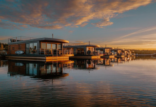 Casa flotante am Bärwalder See al atardecer, casas modernas reflejadas en las tranquilas aguas del lago.