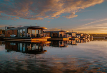 Casa flotante am Bärwalder See al atardecer, casas modernas reflejadas en las tranquilas aguas del lago.