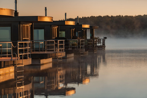 Houseboat «am Bärwalder See» in Germania, riflessi sull’acqua calma al sorgere del sole dorato.