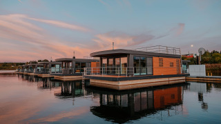 Moderni houseboat am Bärwalder See riflessi sull’acqua calma durante un suggestivo tramonto.