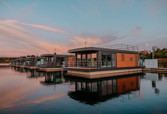 Casa flotante moderna Houseboat am Bärwalder See reflejada en aguas tranquilas al atardecer pintoresco.