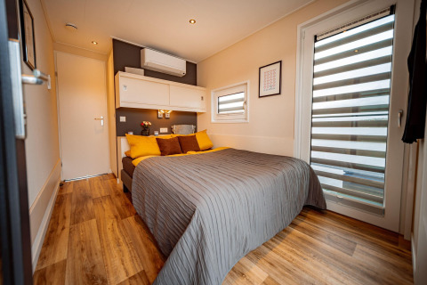 Modern bedroom on Houseboat am Bärwalder See featuring a double bed, wood flooring, and stylish decor.