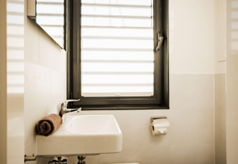 Moderne badkamer op Houseboat am Bärwalder See met wastafel, raam, opgerolde handdoek en wc-rolhouder.
