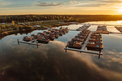 Sunset view of Houseboat am Bärwalder See featuring multiple houseboats anchored peacefully.