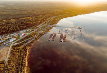 Luftaufnahme vom Houseboat am Bärwalder See mit Hausbooten und Yachthafen bei Sonnenuntergang.