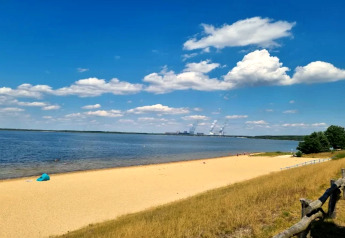 Zicht op een zandstrand en meer met blauwe hemel vanaf Houseboat am Bärwalder See, Duitsland.