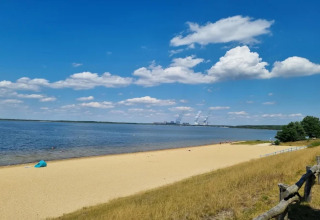 Udsigt over sandstrand og sø med blå himmel og skyer fra Houseboat am Bärwalder See, Tyskland.