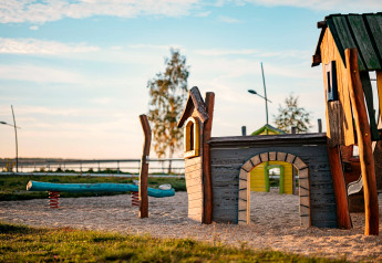 Speelplein bij het meer met houten speelhuisje en wip, genomen bij Houseboat am Bärwalder See.