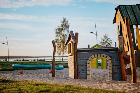Parco giochi sul lago con casetta di legno e altalena, fotografato presso Houseboat am Bärwalder See.