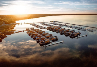 Sunset over houseboats at Bärwalder See in Germany with stunning reflections on the tranquil water.