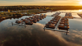 Sunset view of Houseboat am Bärwalder See, featuring houseboats moored on calm water by a forested shore.