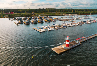 Vista aérea de Houseboat am Bärwalder See, con casa flotante, barcos de vela y un faro rojo y blanco en el muelle.