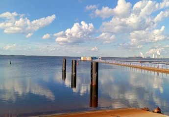 Blick von Houseboat am Bärwalder See mit See, Bojen, Steg und Wolken, die sich im Wasser spiegeln.