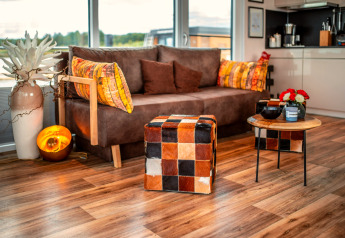 Gemütliches Wohnzimmer auf der Houseboat am Bärwalder See mit bunter Deko, Sofa und Holzboden.