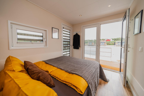 Et hyggeligt soveværelse på Houseboat am Bärwalder See med udsigt over søen fra terrassedøren.