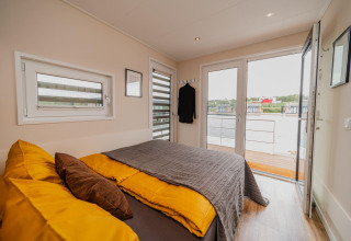 Et hyggeligt soveværelse på Houseboat am Bärwalder See med udsigt over søen fra terrassedøren.