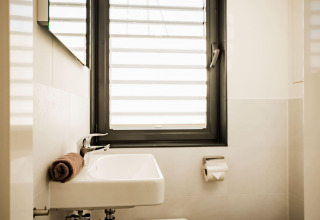 Modern bathroom on Houseboat am Bärwalder See with window, sink, toilet paper roll and a rolled towel.