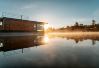 Sonnenaufgang bei dem Hausboot «am Bärwalder See» in Deutschland, gespiegelt im ruhigen Wasser.