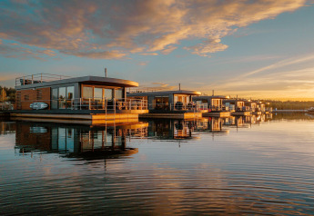 Hausboote am Bärwalder See in Deutschland bei Sonnenuntergang, moderne Ferienunterkünfte am Wasser.