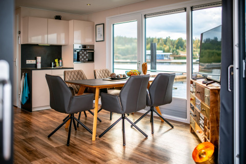 Zona giorno e cucina moderna su una houseboat al Bärwalder See in Germania, con vista panoramica sul lago.