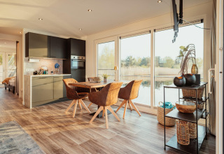 Modern houseboat-interieur aan het Gräbendorfer See met eetruimte, keuken en ramen met zicht op het meer.