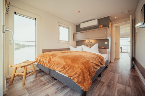 Moderne slaapkamer op een woonboot aan Gräbendorfer See met groot bed en uitzicht op het meer.