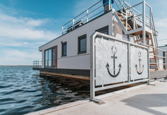 Houseboat sul Gräbendorfer See con ringhiere moderne a tema ancora e acque tranquille circostanti.