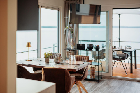 Moderne eetruimte op een woonboot bij Gräbendorfer See in Duitsland, met zicht op het meer en terras.