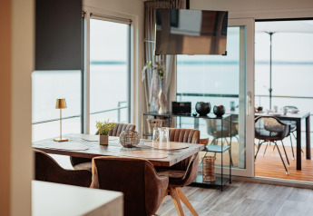 Comedor moderno en una casa flotante en Gräbendorfer See, Alemania, con vistas al lago y al balcón.