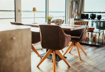 Salle à manger moderne sur la péniche « am Gräbendorfer See » en Allemagne avec mobilier en bois, vue sur le lac.