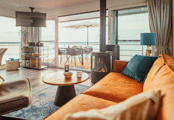 Heldere, moderne woonkamer op Houseboat am Gräbendorfer See met terras en uitzicht op het meer via glazen schuifdeuren.
