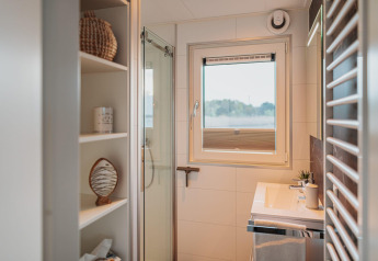 Moderne badkamer op een woonboot aan het Gräbendorfer See met douche, raam en open planken.