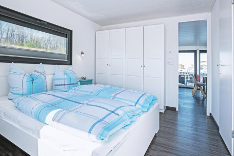 Modern bedroom with blue plaid bedding on houseboat Floating 33 - LP 16 for 4 persons in Germany.