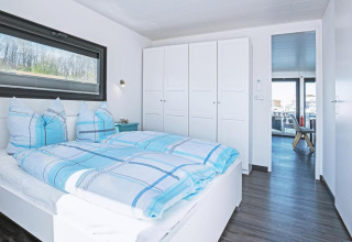 Modern bedroom with blue plaid bedding on houseboat Floating 33 - LP 16 for 4 persons in Germany.