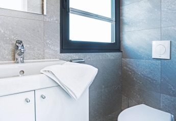 Modernes Badezimmer auf Hausboot mit weißem Waschbecken, Handtuch, Chromarmatur und Fenster.