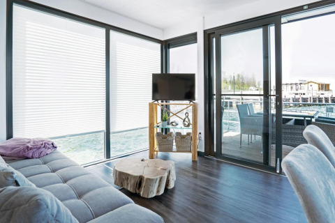 Lichte woonkamer op woonboot Floating 33 - LP 16 in Duitsland met grote ramen en uitzicht op terras.