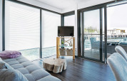 Helles Wohnzimmer auf dem Hausboot Floating 33 - LP 16, Deutschland, mit großen Fenstern und Seeblick.