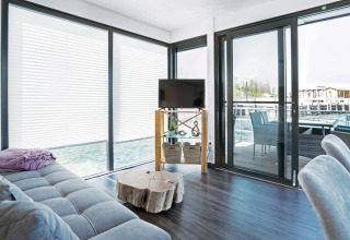 Bright living area on houseboat Floating 33 - LP 16 in Germany with large windows and a view of the deck.