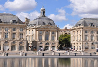 Elegant historic square with classic buildings and reflective water, photographed on a sunny day in Germany.