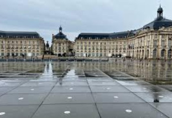 Blick auf den Place de la Bourse in Bordeaux mit spiegelndem Wasserspiegel und klassischer Architektur.