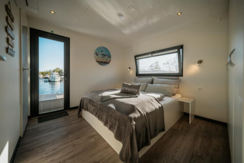 Camera da letto luminosa su una houseboat a Zehdenick con letto matrimoniale e vista sull’acqua.