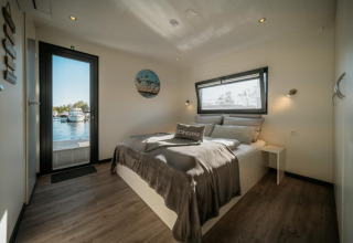Bright, modern bedroom on a houseboat in Zehdenick, featuring a double bed, window and water view.