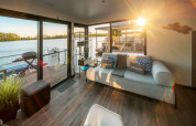 Helles Wohnzimmer auf einem Hausboot in Zehdenick mit Sofa, Seeblick und Zugang zur Terrasse.