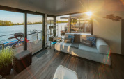 Zonnige woonkamer op een woonboot in Zehdenick met moderne zetel, meerzicht en terras.
