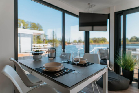 Zona pranzo su houseboat a Zehdenick con vista sull’acqua, grandi finestre e arredo moderno.